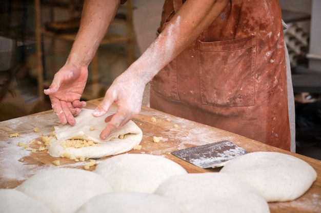 Detalhe das mãos de um padeiro introduzindo ingredientes na massa de pão. Foto de alta qualidade