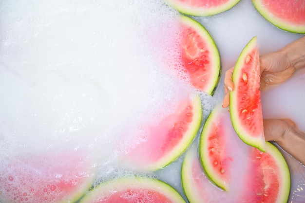 Detalhe das mãos de uma mulher segurando uma fatia de melancia Garota toma banho com leite e frutas para rejuvenescer a pele Cuidados com o corpo