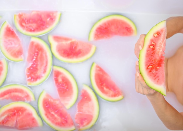 Detalhe das mãos de uma mulher segurando uma fatia de melancia Garota toma banho com leite e frutas para rejuvenescer a pele Cuidados com o corpo