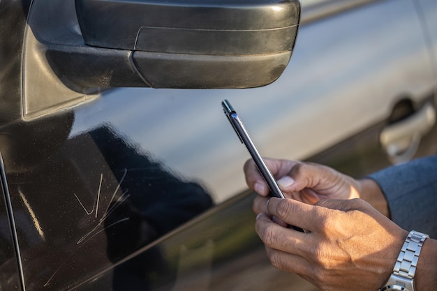 Detalhe das mãos do agente de seguros tirando uma foto de um carro com um arranhão