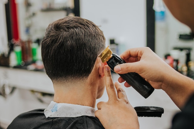 Detalhe das mãos do barbeiro cortando o cabelo do cliente