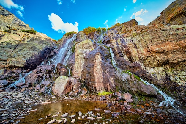 Detalhe de cachoeira sobre rochas cobertas de musgo em montanhas rochosas