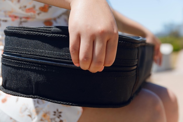 Detalhe de closeup de mão feminina fechando caixa de violino sentada ao ar livre