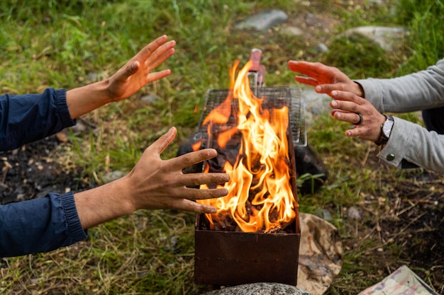 Detalhe de dois homens aquecendo as mãos perto do fogo