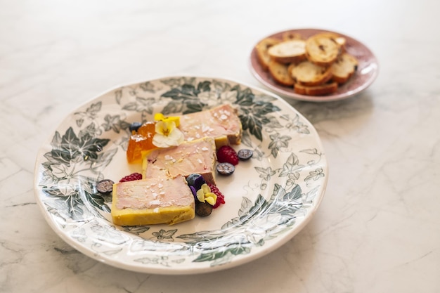 Detalhe de foie gras delicioso com bagas e flores comestíveis s em um prato ornamentado