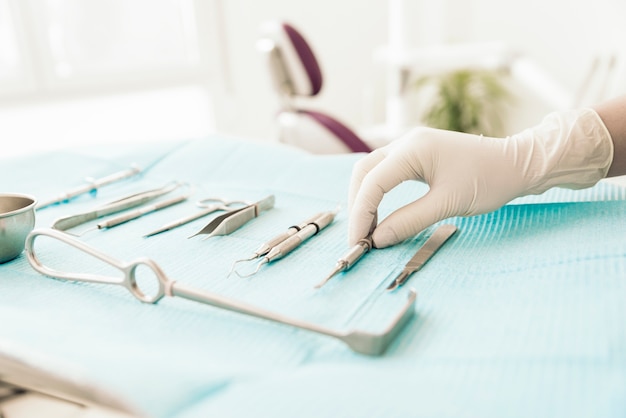 Detalhe de mão segurando ferramentas dentais na clínica odontológica. Conceito de dentista.