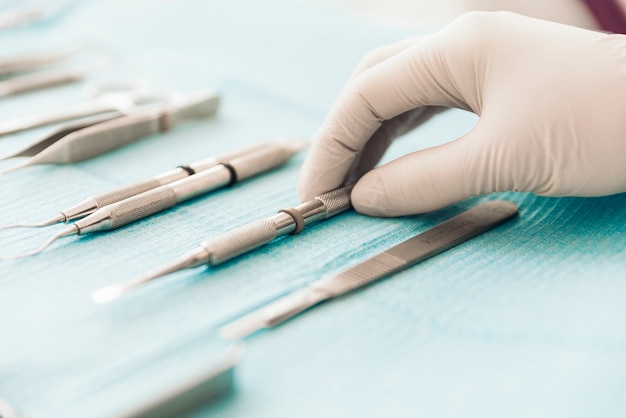 Detalhe de mão segurando ferramentas dentais na clínica odontológica. Conceito de dentista.