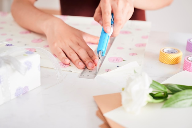 Detalhe de mãos de mulher embalando presentes com papel de presente