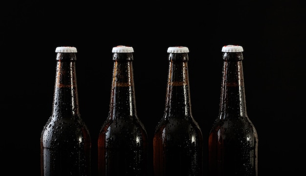 Detalhe de quatro garrafas de cerveja isoladas em fundo preto