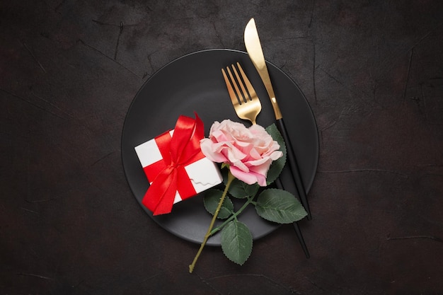 Detalhe de rosa, faca, garfo e presentes em um prato