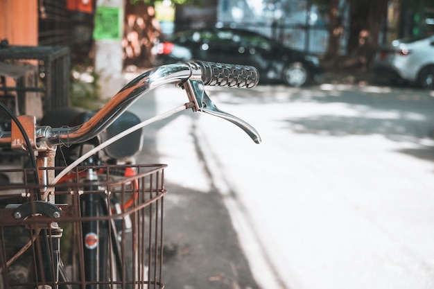 Detalhe de um guidão de bicicletas vintage estacionado na rua estreita urbana (estilos de tom de cor vintage)