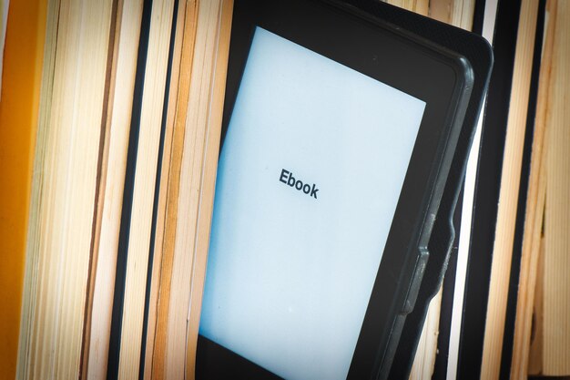 Detalhe de um leitor de ebook entre livros clássicos