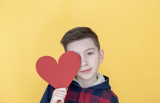 Detalhe de um menino segurando um coração recortado de papel