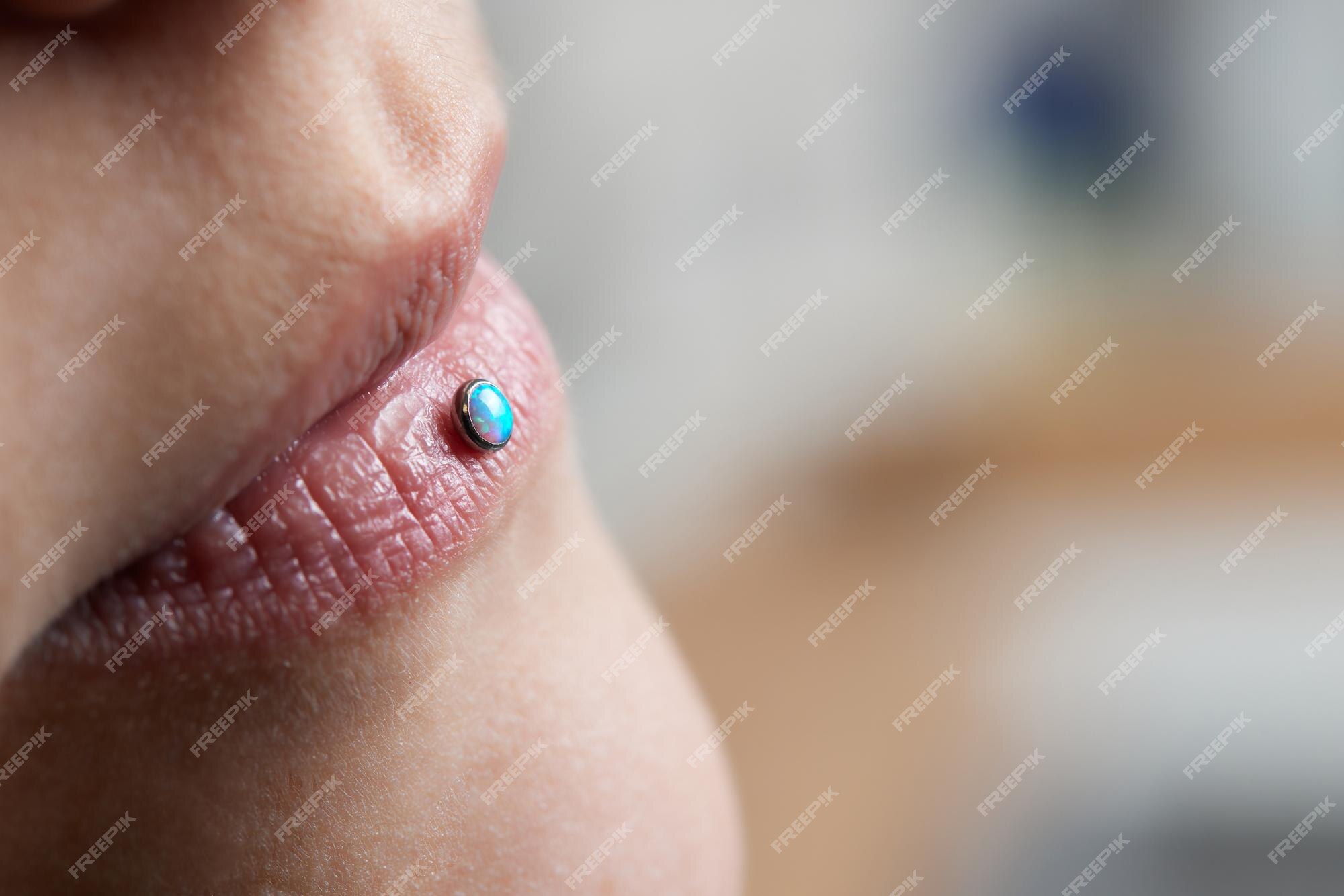 Detalhe de um piercing labret na boca de uma mulher sorridente