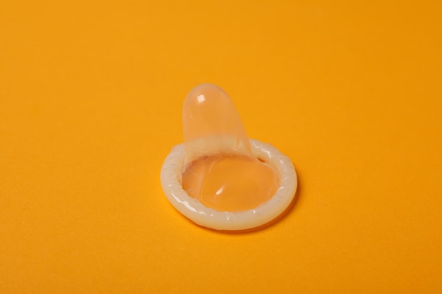 Detalhe de um preservativo descompactado em um fundo amarelo