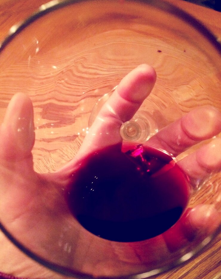 Foto detalhe de uma mão segurando um copo de vinho vermelho