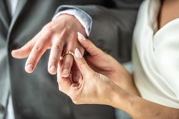 Detalhe de uma noiva colocando um anel no dedo de um noivo durante uma cerimônia de casamento