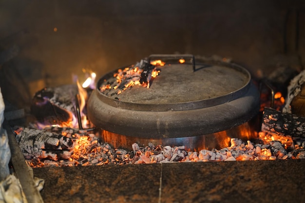 Detalhe de uma panela no fogo com uma pilha de madeira