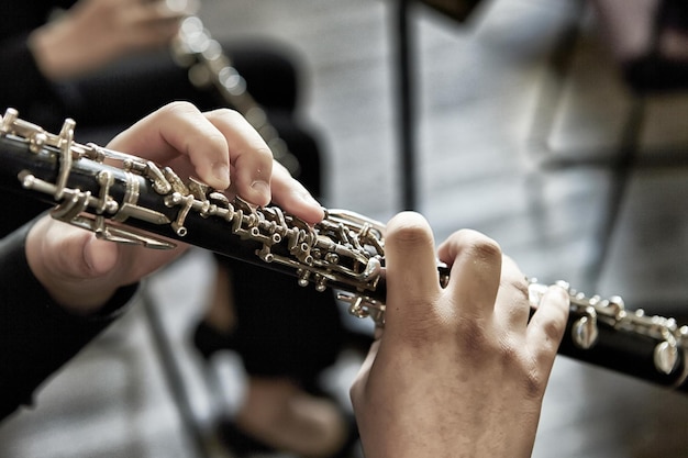 Detalhe de uma pessoa tocando oboé, dentro de casa