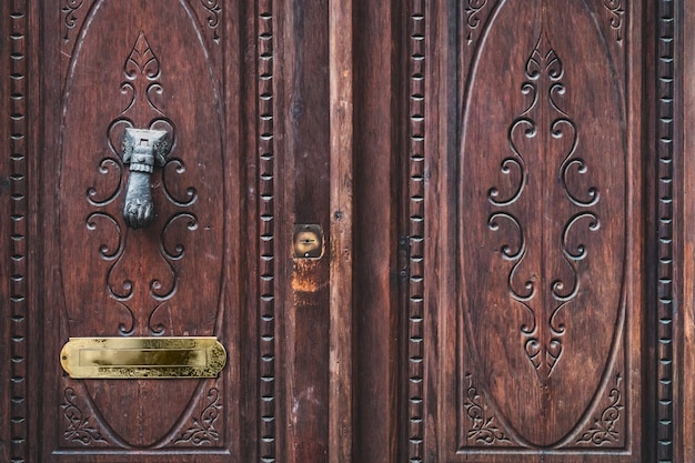 Detalhe de uma porta velha de madeira entalhada com uma aldrava de mão antiga