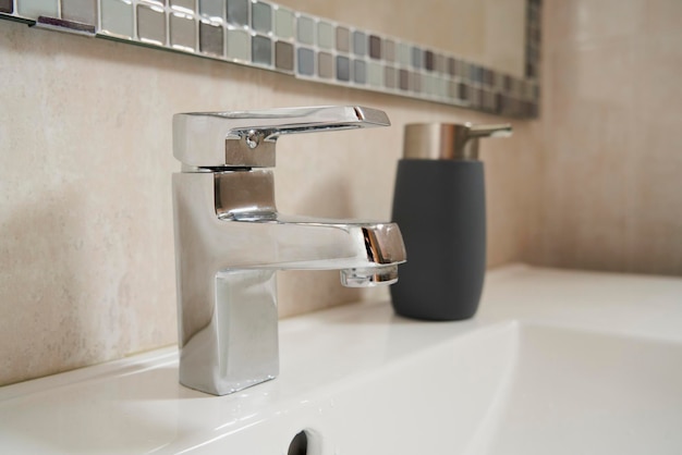 Foto detalhe de uma torneira de banheiro prateada e dispensador de sabão