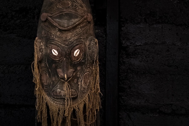 Detalhe de uma velha máscara ritual feita de madeira em um fundo preto. atributo ritual. copie o espaço