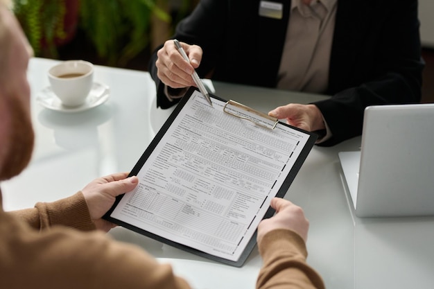 Detalhe do consultor de seguros entregando o formulário de inscrição ao cliente durante a consulta