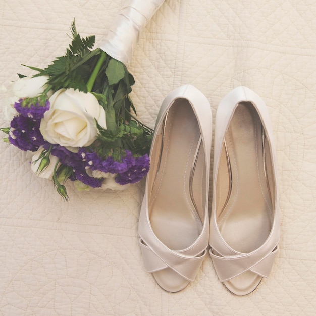 Detalhe do dia do casamento Sapatos de noiva e buquê