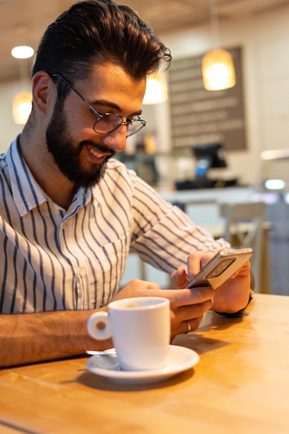 Detalhe do jovem verificando o celular dentro de uma padaria