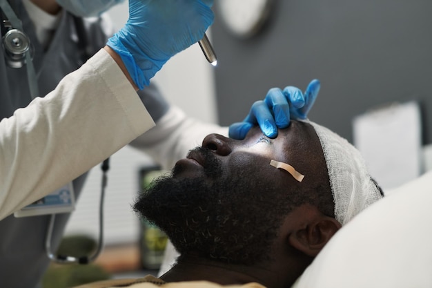 Detalhe do médico abrindo o olho do paciente ferido enquanto direciona a luz para lá