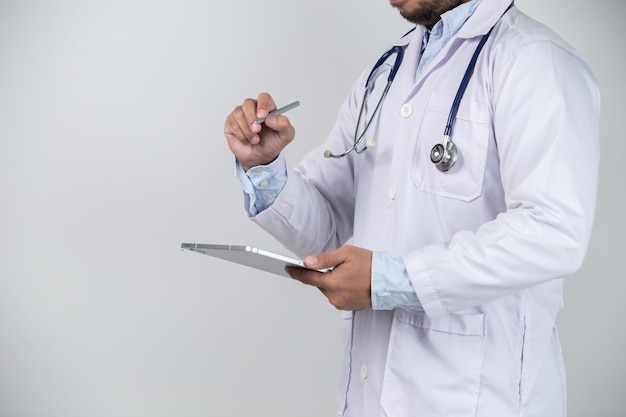 Detalhe do médico masculino usando tablet digital em fundo cinza