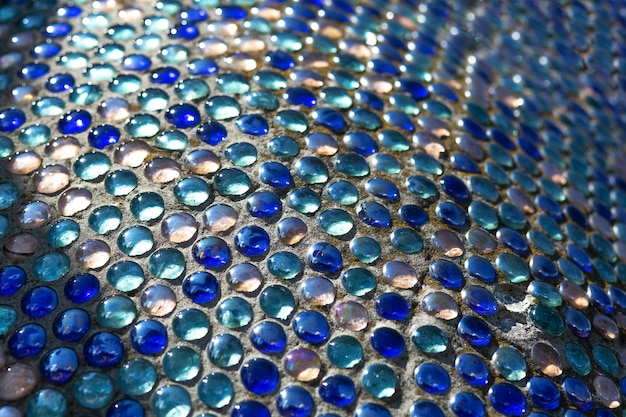 Detalhe do mosaico de vidro abstrato azul na rua com a luz do sol. Foco seletivo