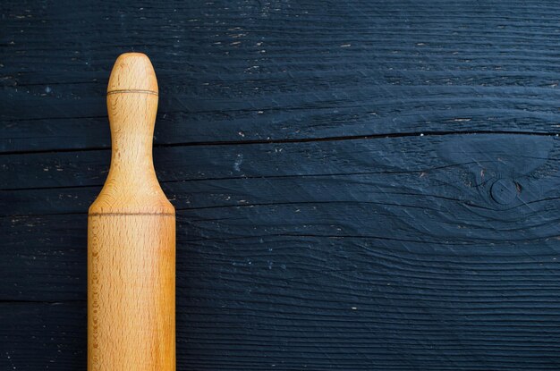 Detalhe do pino de madeira rolando sobre a mesa de madeira preta horizontal e vista acima com espaço de cópia para texto ou outro design