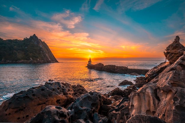 Detalhe do sol atrás do farol ao pôr do sol na cidade de pasajes san juan