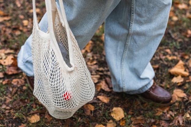 Detalhe dos pés do homem andando no parque com saco plástico para reciclagem