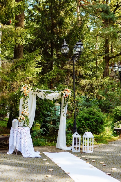 Foto detalhes da decoração do casamento arco branco árvores verdes ao fundo cerimônia ao ar livre