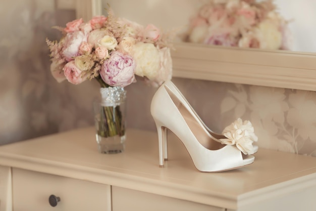 Detalhes do casamento bouquet de noiva e sapatos de salto alto marfim