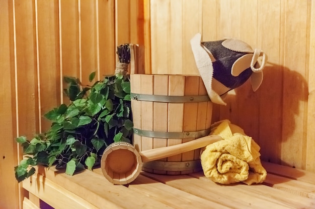 Detalhes do interior Sauna finlandesa sauna a vapor com acessórios de sauna tradicional bacia bétula vassoura colher feltro toalha para chapéu. Conceito de SPA de balneário russo antigo tradicional. Conceito de banho de vila rural relaxante