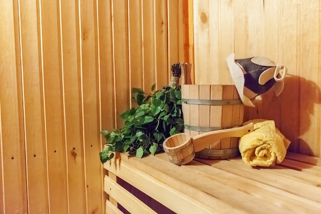 Detalhes do interior Sauna finlandesa sauna a vapor com acessórios de sauna tradicional bacia bétula vassoura colher feltro toalha para chapéu. Conceito de SPA de balneário russo antigo tradicional. Conceito de banho de vila rural relaxante