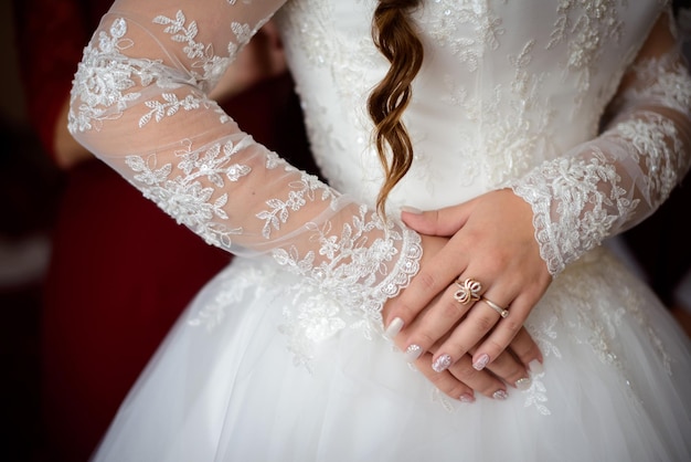 Detalhes do lindo vestido de noiva de renda e mãos femininas com anéis dourados feche as mãos de uma noiva e vestido branco para casamento