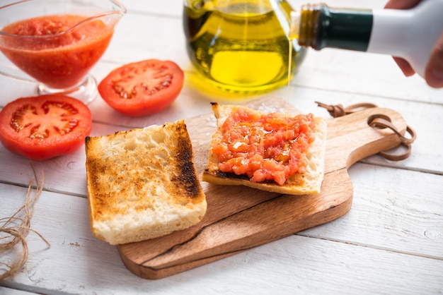 Detalle de aceite cayendo sobre una tostada con tomate desayuno saludable