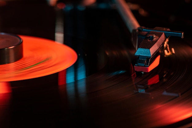 Detalle de la aguja en el disco de vinilo en el tocadiscos, imagen con poca luz con reflejo