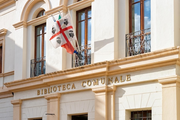 Foto detalle de la arquitectura del edificio de la biblioteca comunale, o biblioteca pública con bandera sarda colgante en olbia en la isla de cerdeña en italia.
