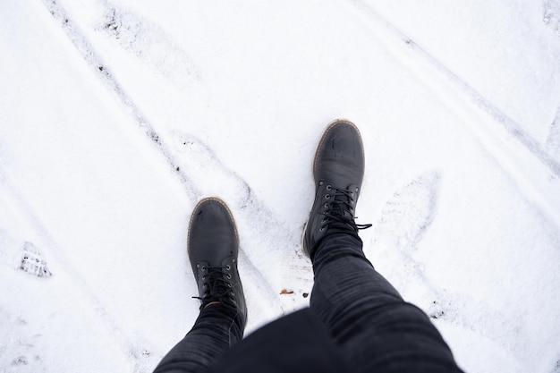 Detalle de las botas de un hombre irreconocible en la nieve con botas de concepto de invierno