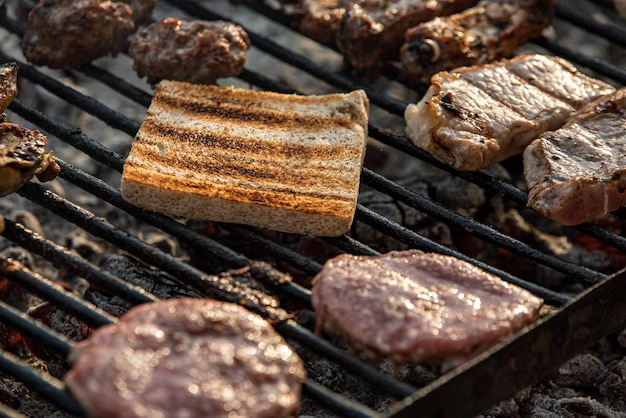 Detalle de carnes y pan a la brasa, cocinando a la parrilla