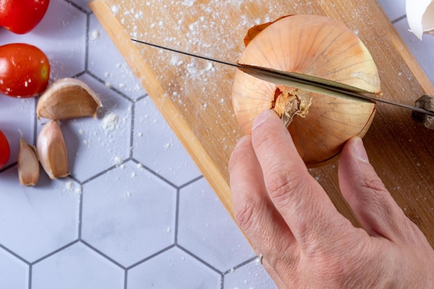 Detalle de una cebolla cortada a mano entre ingredientes y utensilios de cocina