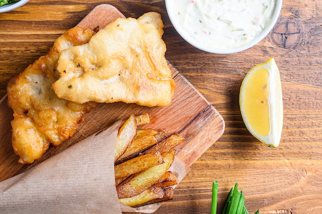 Detalle de chips de pescado con dip y limón, puré de guisantes de menta, salsa tártara en cono de papel