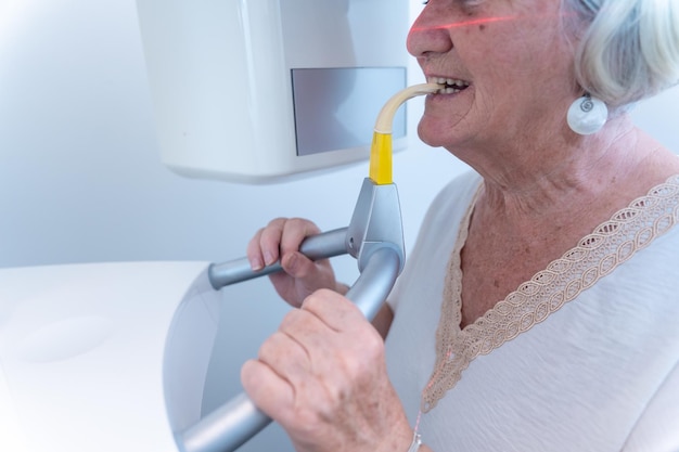 Detalle de la clínica dental de una anciana en la sala de rayos x realizando una radiografía