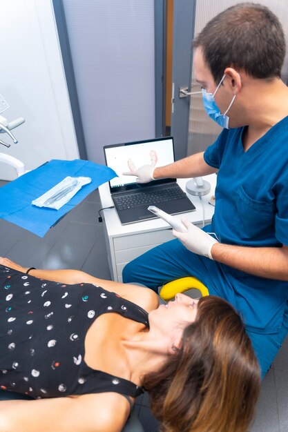 Foto detalle de la clínica dental del dentista que realiza un escaneo 3d del paciente acostado