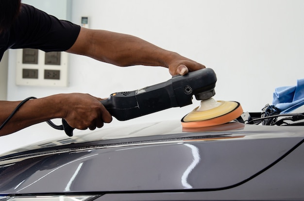 Detalle del coche: mecánico masculino que sostiene la máquina pulidora de coches. Industria automotriz, taller de pulido y pintura y reparación de automóviles.